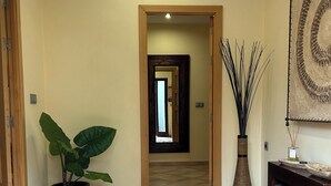 A hallway with a potted plant, a rug, and a tall vase.
