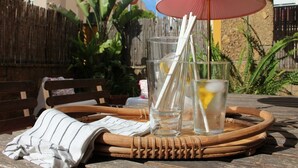 A wicker tray with two glasses of water, a straw, and a lemon slice on a table outdoors.