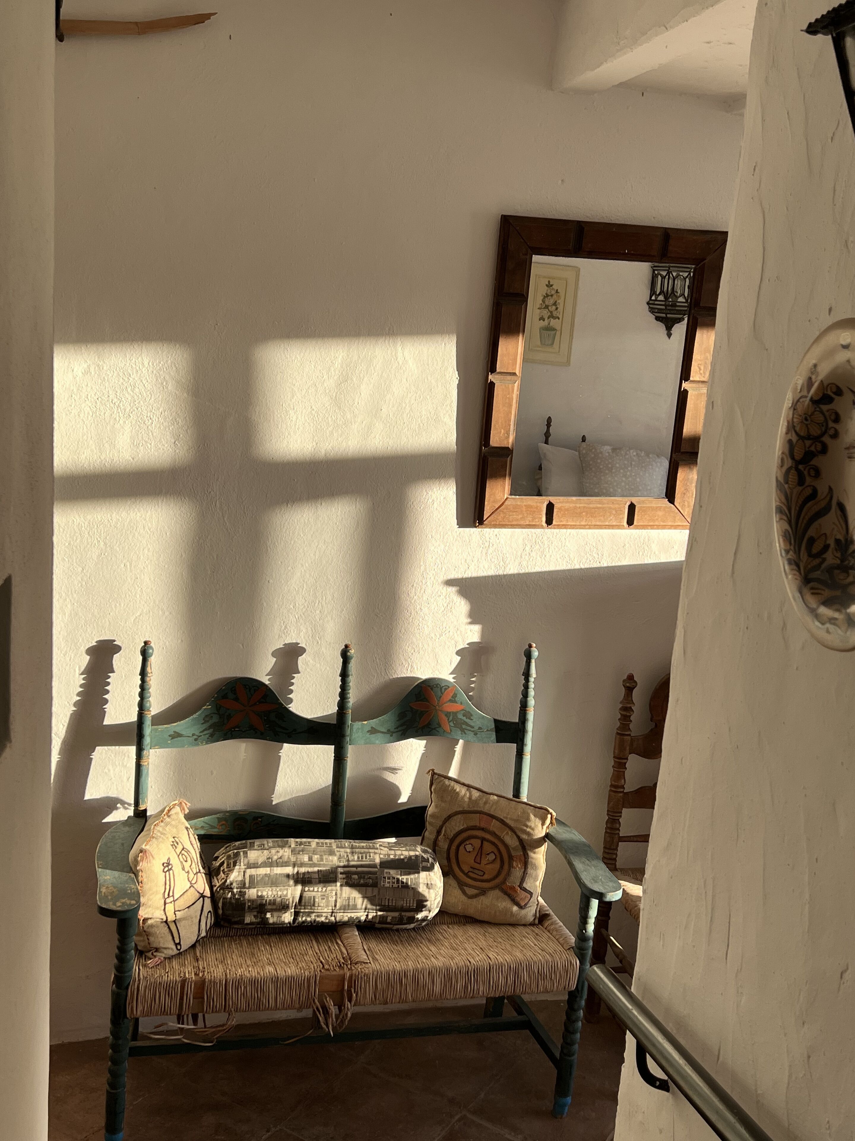 Une pièce rustique avec un banc en bois, un miroir et un coussin à motifs.