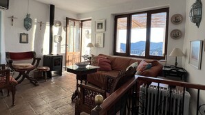 A cozy living room with a fireplace, a sofa, and a dining table. - Large Four bedroom house in exquisite 16th century Moorish village. Sleeps 8. (Frigiliana, Nerja)
