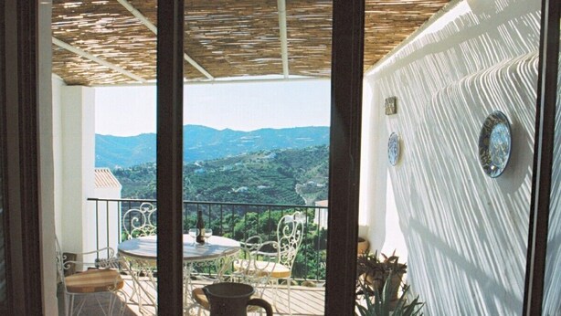A balcony with a view of a mountainous landscape, a table with chairs, and a decorative vase. - Large Four bedroom house in exquisite 16th century Moorish village. Sleeps 8. (Frigiliana, Nerja)