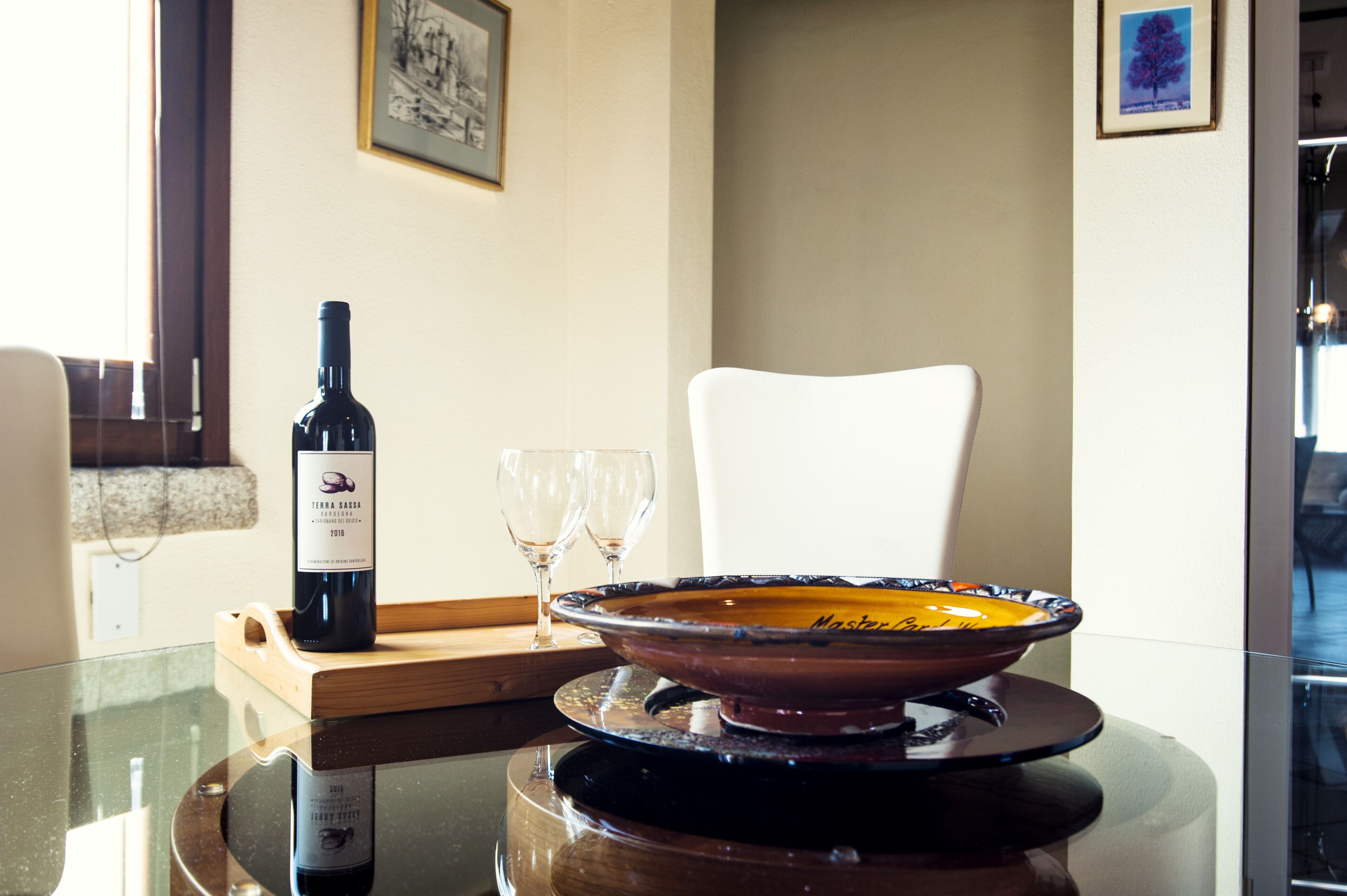 Une table à manger avec une bouteille de vin, deux verres et un bol décoratif.