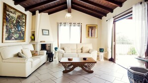 A living room with a white sofa, a wooden coffee table, and a painting on the wall. - Beautiful Villa Layla with pool (Castiadas)