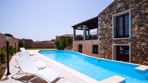 A swimming pool with lounge chairs, a stone building, and a clear sky. - Beautiful Villa Layla with pool (Castiadas)