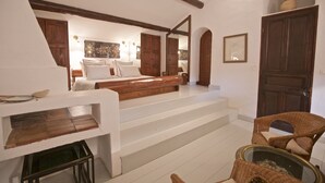 A bedroom with a wooden staircase, a bed with white linens, a wicker chair, and a glass coffee table. - Beautifully renovated Artist’s farmhouse in Provence, large heated pool & sauna (Roussillon)