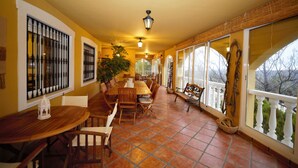 A dining area with a wooden table and chairs, a potted plant, and a view through large windows. - Villa 15min from Alicante, free WiFi, indoor pool, ideal for families.  (Tibi)