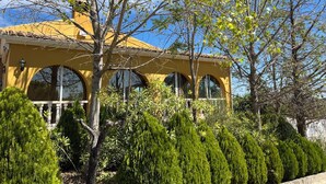 A yellow building with arched windows and a tiled roof, surrounded by lush greenery. - Villa 15min from Alicante, free WiFi, indoor pool, ideal for families.  (Tibi)