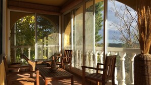 A sunlit patio with wooden furniture and large windows offering a view of trees and hills. - Villa 15min from Alicante, free WiFi, indoor pool, ideal for families.  (Tibi)