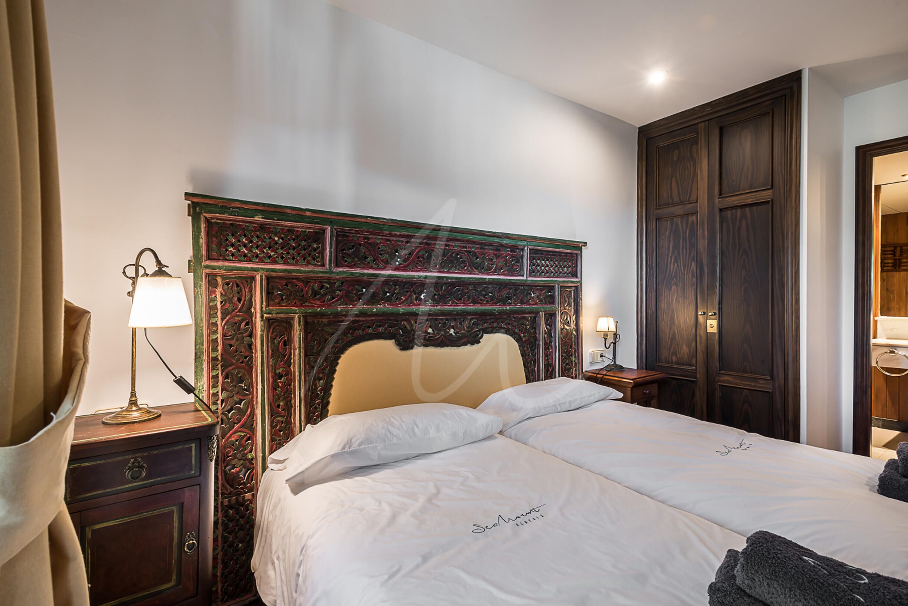 Une chambre d’hôtel avec un grand lit, une table de chevet avec une lampe et une armoire.