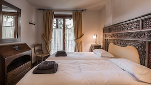 Une chambre avec deux lits, une commode en bois, une chaise et une fenêtre avec des rideaux.