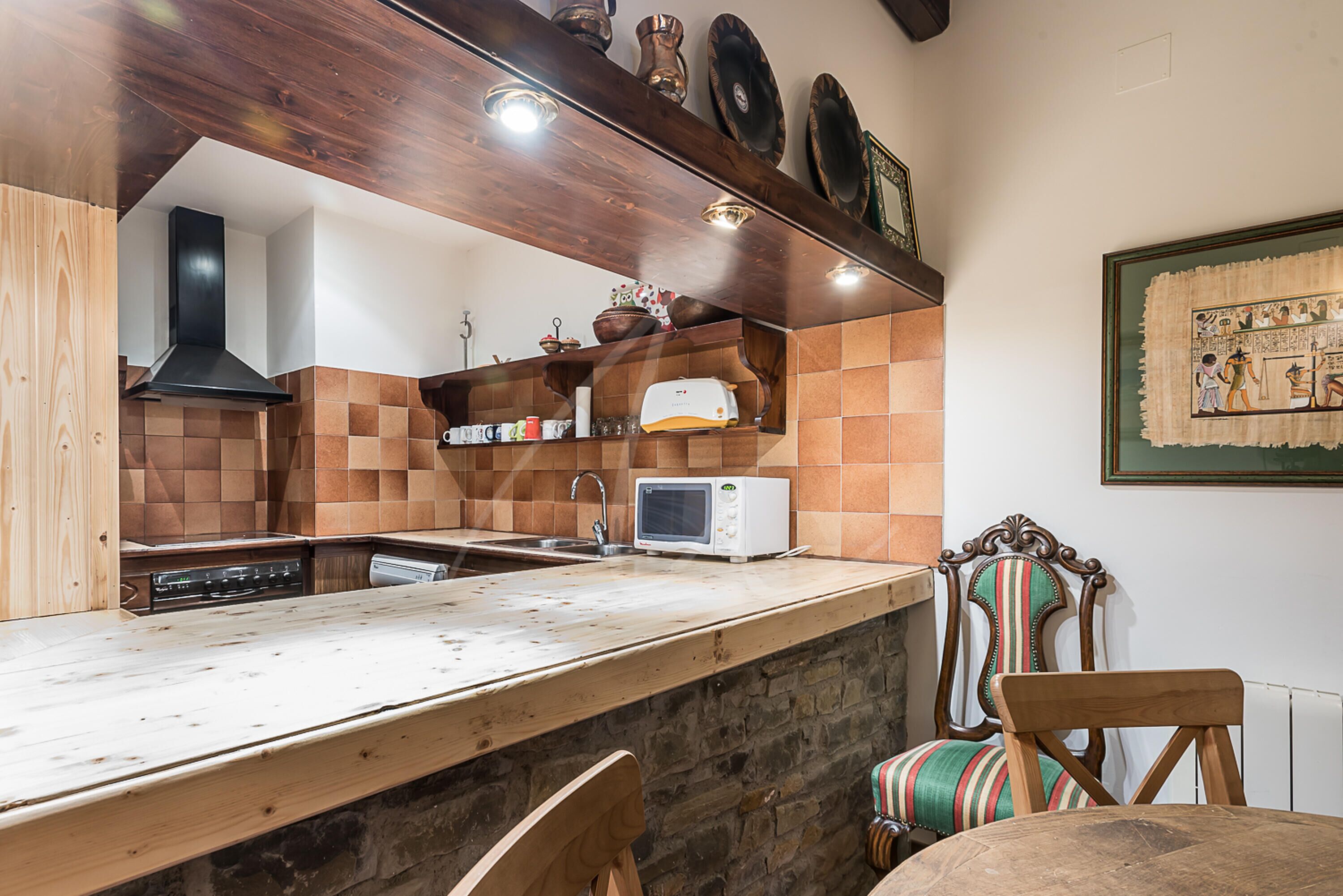 Una cocina con mostrador de madera, microondas y pileta.
