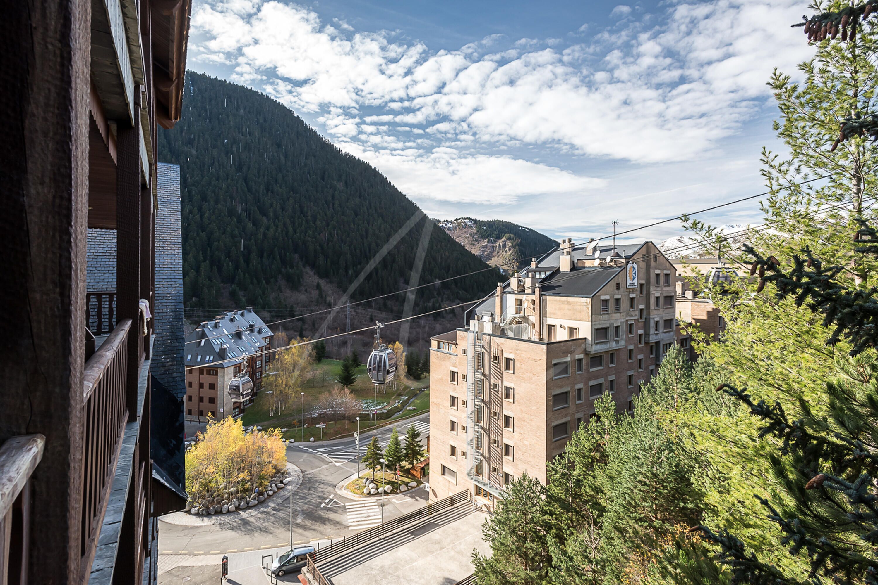 Une ville de montagne dotée d’un téléphérique, de bâtiments et entourée d’une vallée boisée.