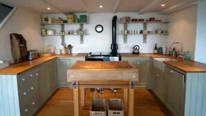 A kitchen with wooden cabinets, a central island, and built-in shelves with various kitchen items.