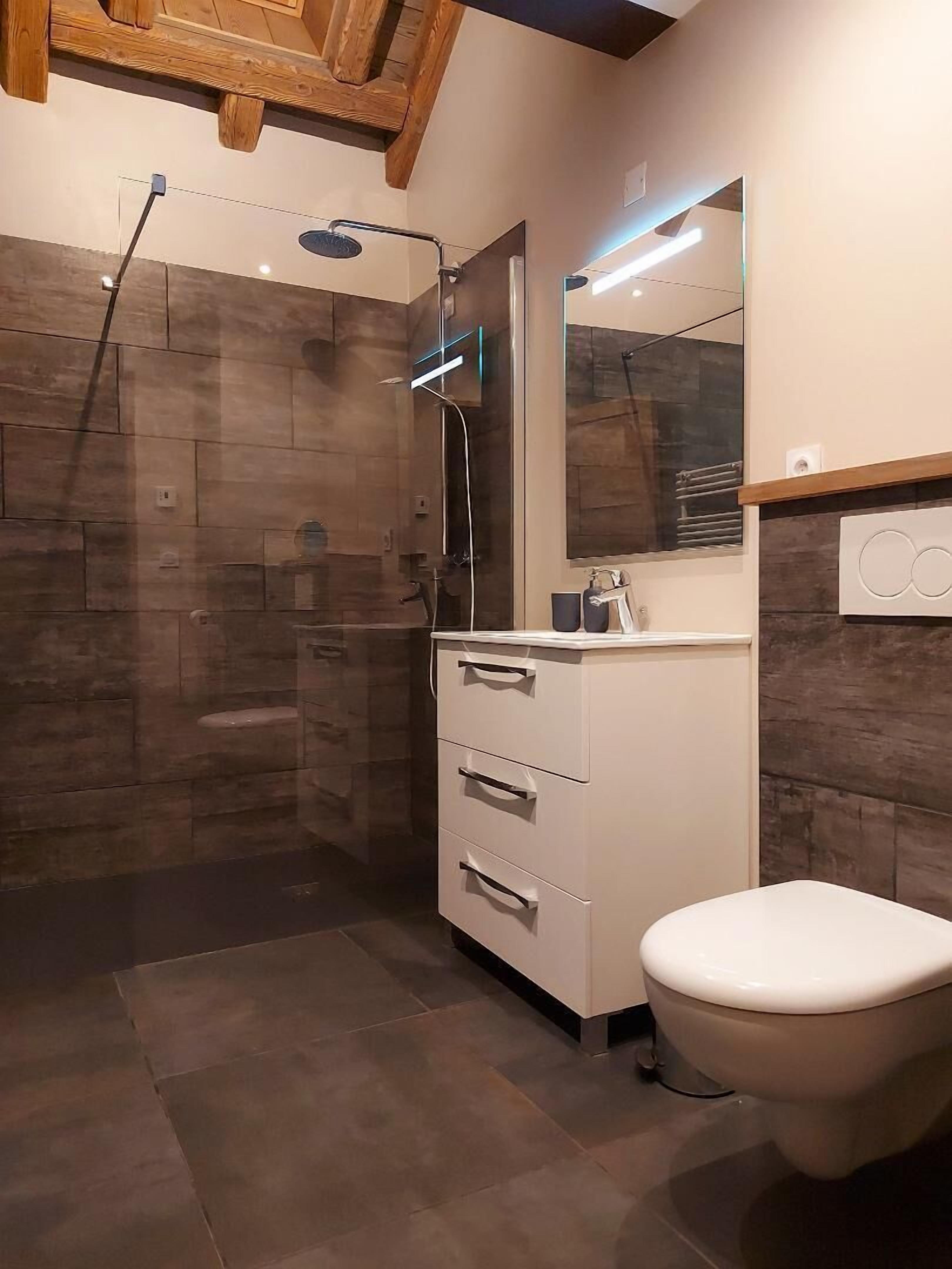 Un bagno moderno con doccia, un water e un mobile lavabo con cassetti.