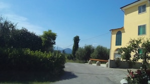 A yellow building with a paved driveway and a clear blue sky. - Big panoramic house in the Lucca hills. Pool, garden, WiFi, Aircon (Capannori)