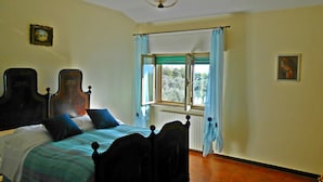 A bedroom with a bed, a window with curtains, a chandelier, and a painting on the wall. - Big panoramic house in the Lucca hills. Pool, garden, WiFi, Aircon (Capannori)