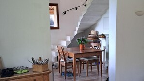 A spacious living area with a wooden dining table, a sofa, and a staircase leading to another room. - Lovely Family Home With Pool, Complete Privacy And Views Over The Lubero  (Forcalquier)