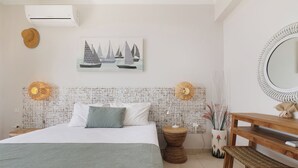 A neatly arranged bedroom with a bed, bedside tables, a mirror, and a wall-mounted artwork.