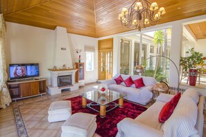 A living room with a fireplace, a sofa set, a television, and a large window.