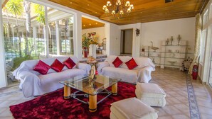 A living room with a glass coffee table, two sofas with red cushions, a red rug, and a wooden ceiling. - Villa Lira | 6 bedrooms | Spacious | Quinta do Lago (Quinta do Lago)