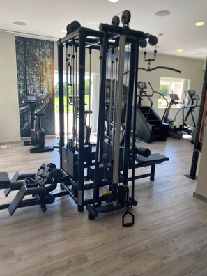 A gym with cardio machines, weightlifting equipment, and a large window with a view of outdoor scenery.