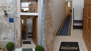 Ein Hotel Eingangsbereich mit Fußmatte, einer Rezeption und einer Treppe, die nach innen führt.