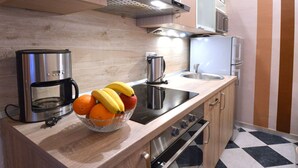 Eine moderne Küche mit integriertem Backofen, einer Kaffeemaschine, einem Wasserkocher und einer Obstschale auf der Arbeitsfläche.