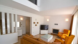 Una sala de estar moderna con un sofá, sillones, un televisor y una chimenea.