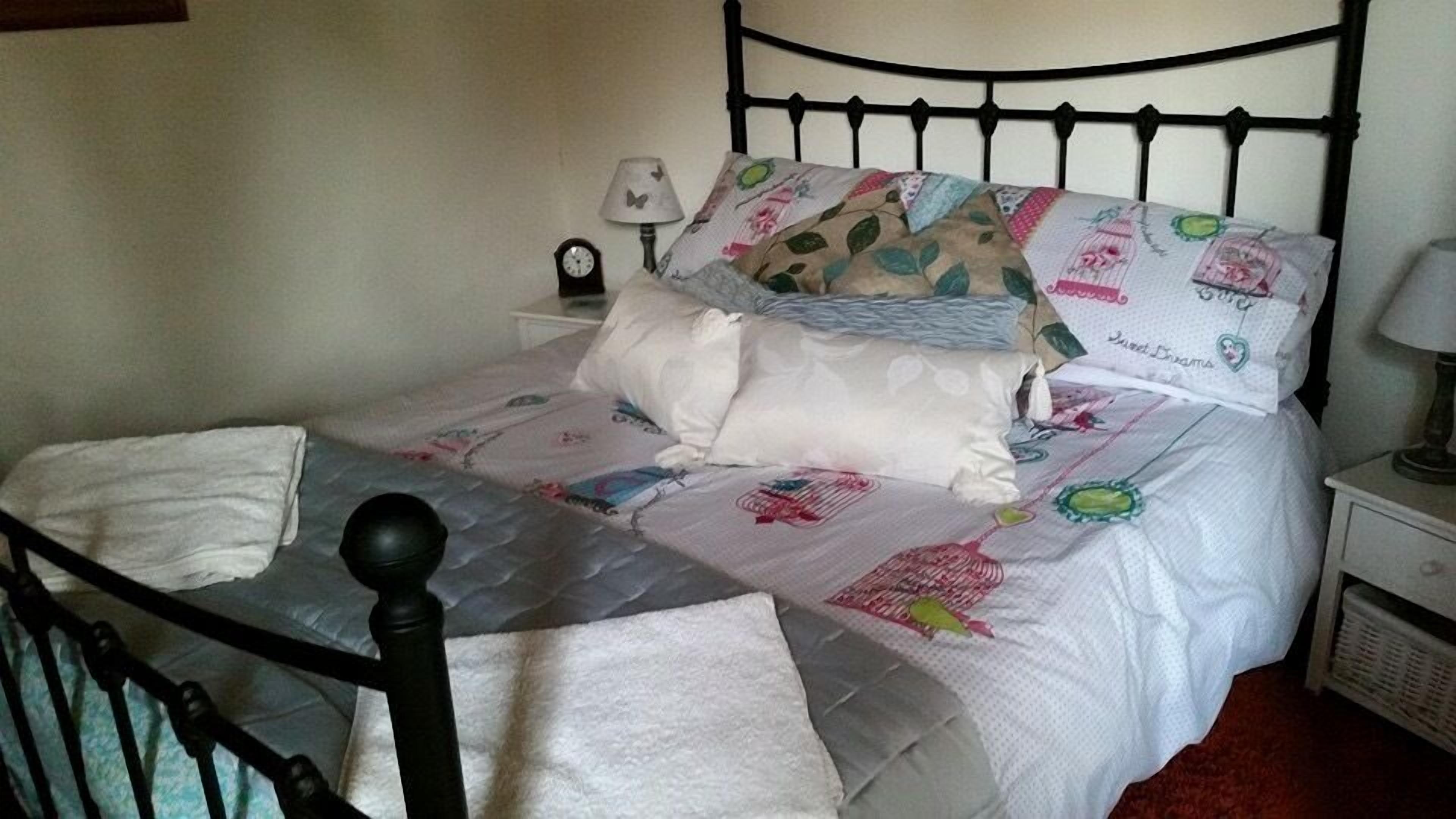 Un lit bien fait, avec une couette à motifs floraux, des oreillers et une lampe de chevet.