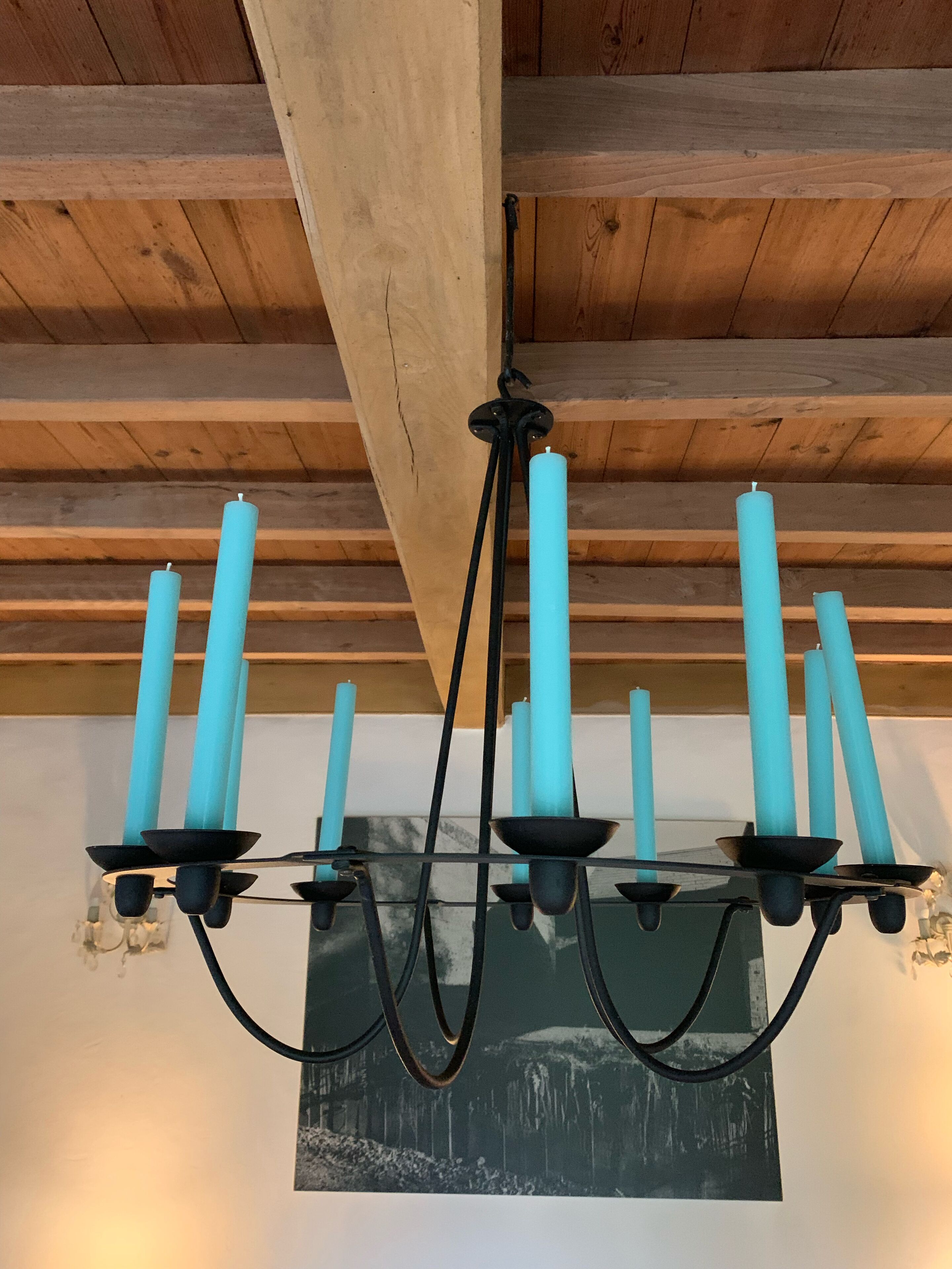 Un candelabro con múltiples velas color turquesa colgando de una estructura de techo de madera.