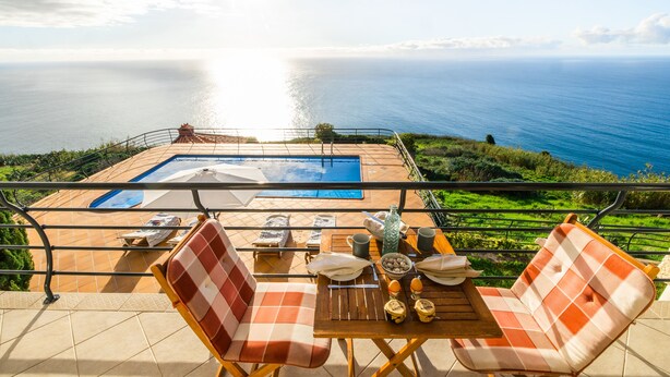 A terrace with a pool, outdoor seating, and a view of the ocean. - Secluded Sunset Villa on Cliff & 180° Ocean Views (Calheta)