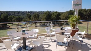 A terrace with white plastic chairs and tables, a potted plant, and a sign reading "Estrella de Levante". - Beautiful apartment with private pool, wifi, tv, close to all amenities (Orihuela Costa)
