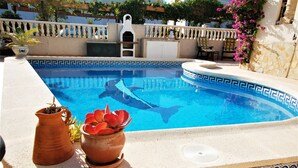 A swimming pool with a decorative edge, surrounded by a tiled deck and potted plants. - Beautiful apartment with private pool, wifi, tv, close to all amenities (Orihuela Costa)