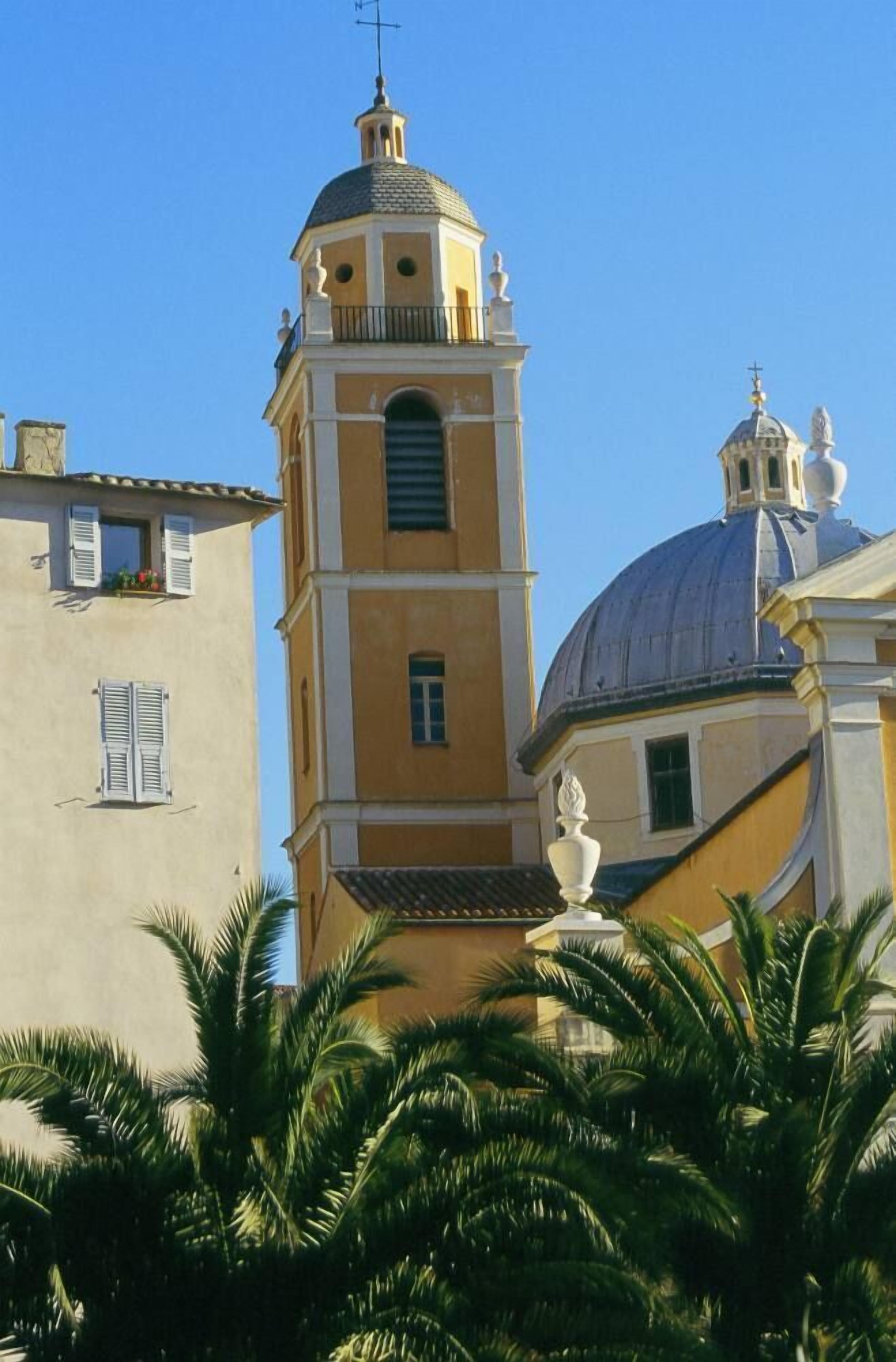 A building with a prominent bell tower and a dome, surrounded by palm trees.