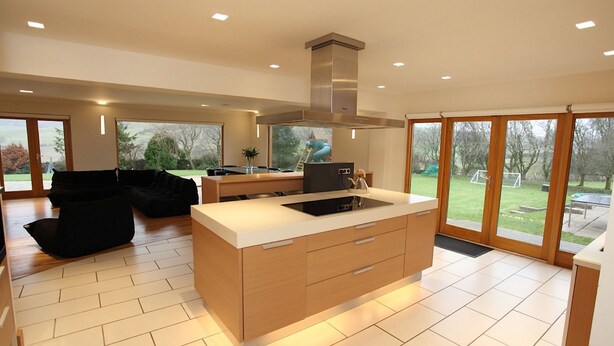 A modern kitchen with a central island, large windows, and a view of the outdoors.