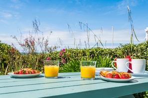 Une table garnie de nourriture et de boissons, entourée de verdure.
