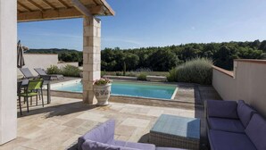 Un espace piscine aménagé sur le toit, avec des chaises longues, une table et un pot de fleurs.