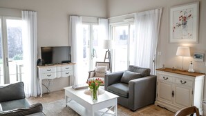 Un salon moderne avec un canapé gris, une table basse blanche et un téléviseur posé sur un meuble en bois.