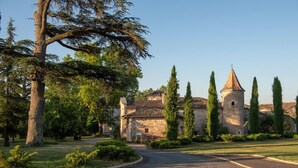 A historic stone building with a tower, surrounded by a well-maintained lawn and tall trees. - Villa Corduriès - air conditioning & heated swimming pool in the castle grounds (Castelnau de Montmiral)