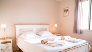 A neatly made double bed with white linens, two bedside tables with lamps, and a window with curtains. - Villa Corduriès - air conditioning & heated swimming pool in the castle grounds (Castelnau de Montmiral)