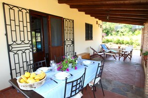 A dining area with a table set for two, a bowl of fruit, and a potted plant.