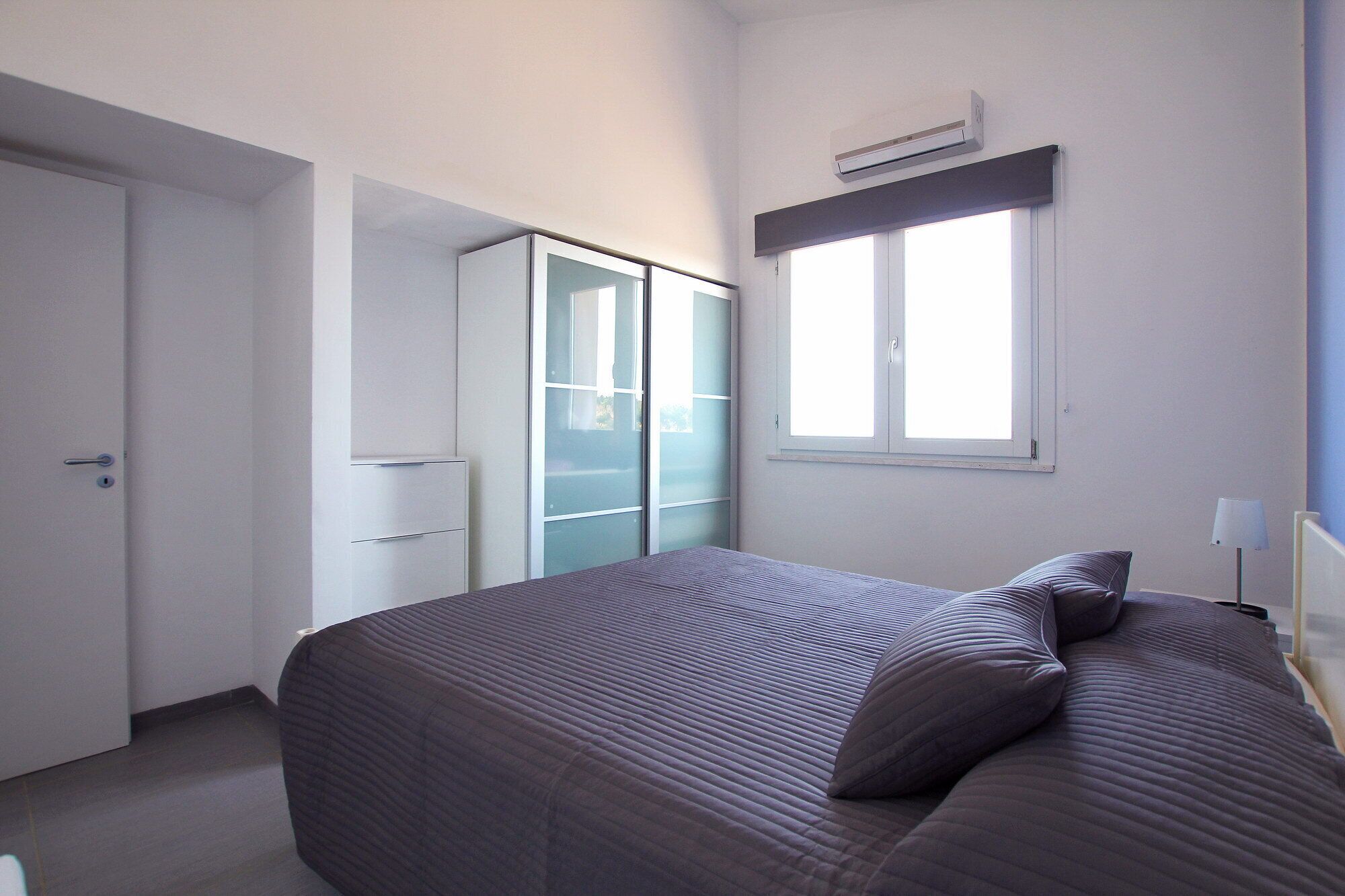 Un dormitorio con cama, armario y ventana.
