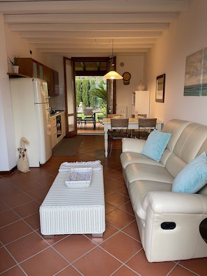 A living room with a sofa, a coffee table, and a dining area with chairs and a table.