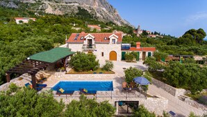 A stone villa with a swimming pool, a covered patio, and a view of a mountainous landscape. - Villa Oliva - exclusive gateway, luxurious serenity, stunning views, heated pool (Podgora)
