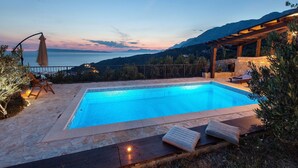 A swimming pool with a view of the sea and mountains at dusk. - Villa Oliva - exclusive gateway, luxurious serenity, stunning views, heated pool (Podgora)