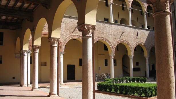 A courtyard with arches and columns, a brick building, and a well-maintained hedge. - Beautiful and spacious apartment, with garage, in an ancient building in the city center.  (Ferrara)