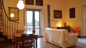 A room with a bed, a table with chairs, a staircase, and artwork on the walls. - Beautiful and spacious apartment, with garage, in an ancient building in the city center.  (Ferrara)