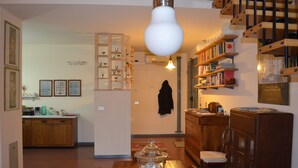 A cozy living room with a wooden dining table, a coffee table, and a bookshelf filled with books. - Beautiful and spacious apartment, with garage, in an ancient building in the city center.  (Ferrara)