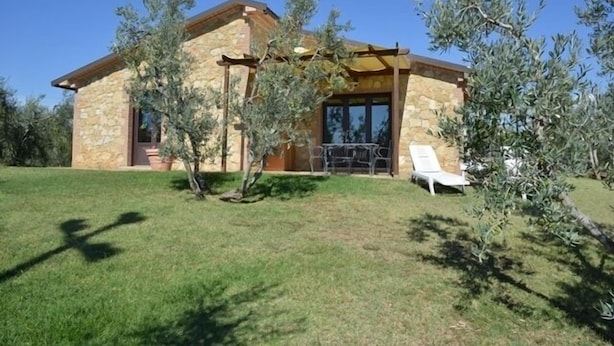 A stone house with a pergola, a lawn, and two white lounge chairs. - Detached house, stone, 6 pax, garden, wonderful sea view (Casale Marittimo)
