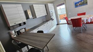 Une cuisine moderne dotée d’appareils électroménagers intégrés, un coin repas avec des chaises rouges et une vue sur l’extérieur.